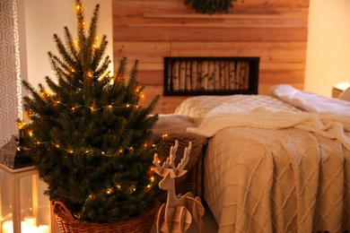 Photo of Beautiful decorated Christmas tree with fairy lights in bedroom interior