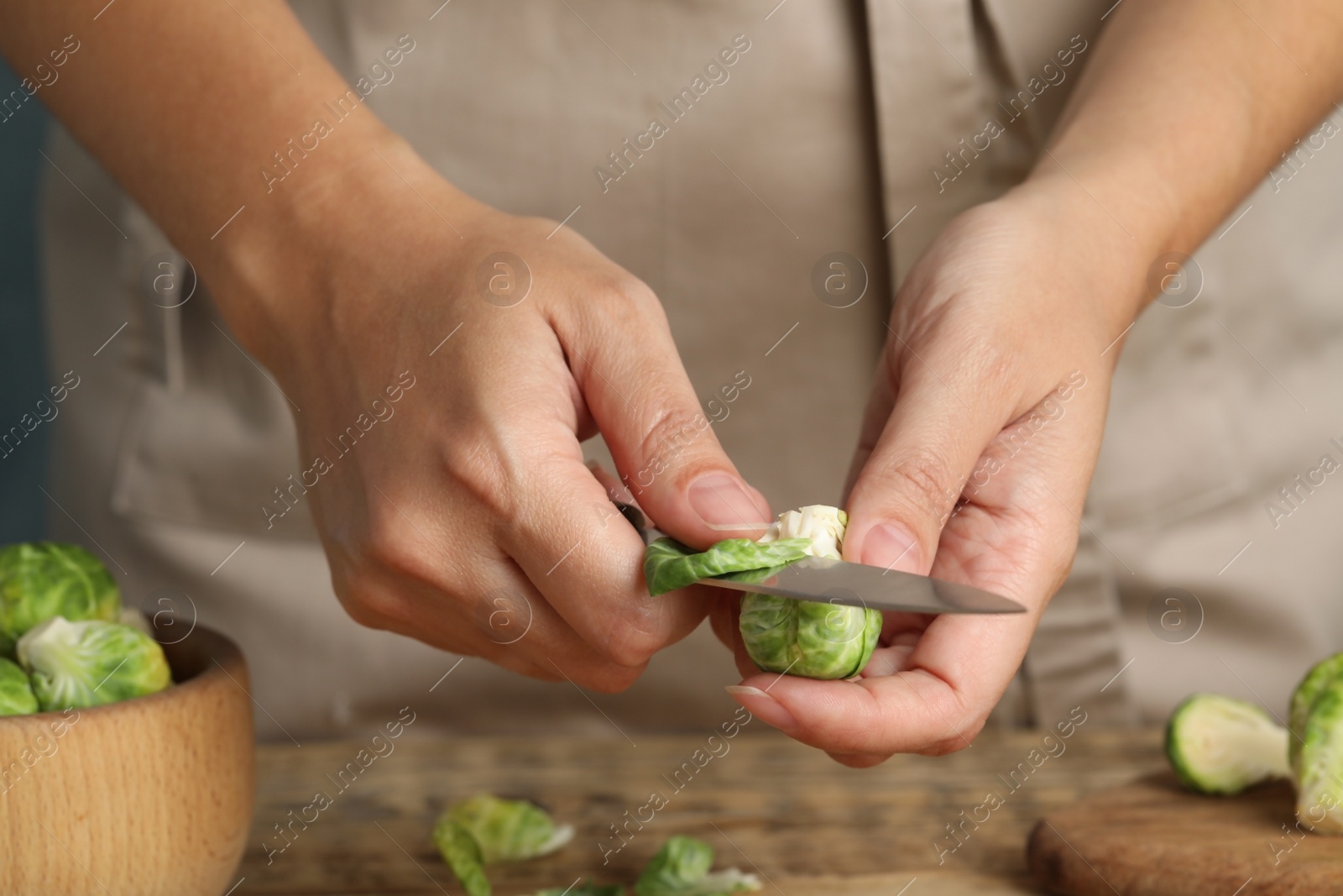 Photo of Woman peeling Brussels sprout at table, closeup