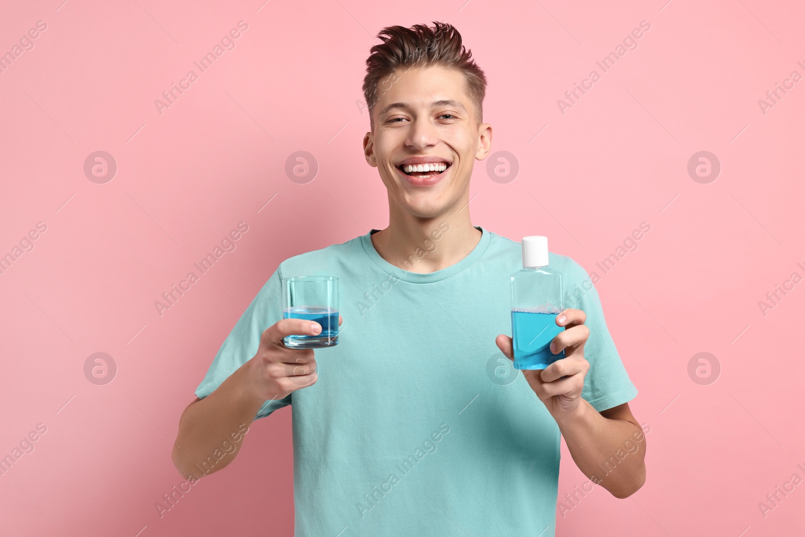 Photo of Young man with mouthwash on pink background