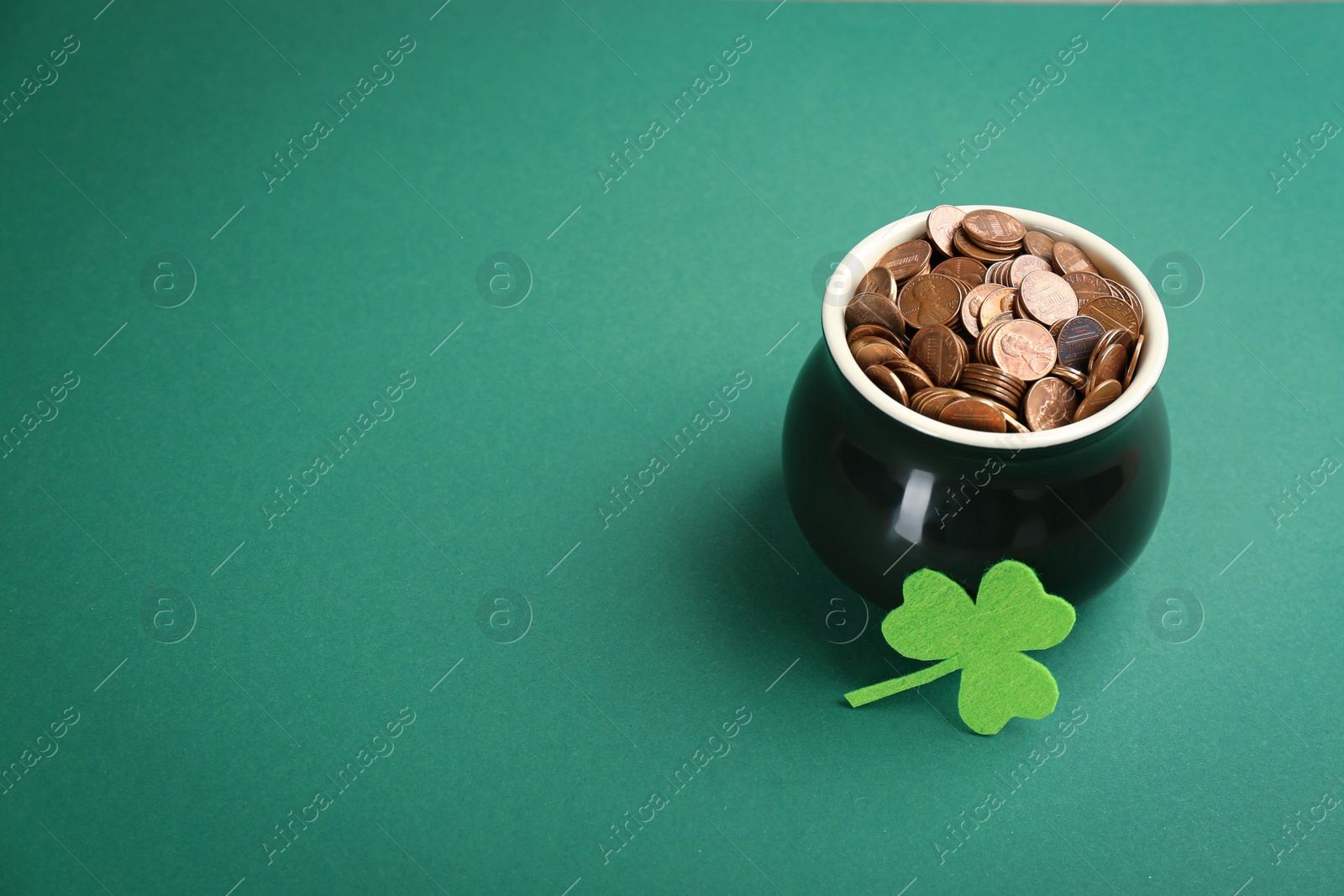 Photo of Pot of gold coins and clover on green background, space for text. St. Patrick's Day celebration