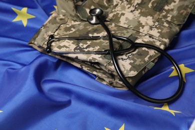 Photo of Stethoscope and military uniform on flag of European Union, closeup