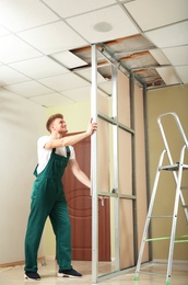 Young worker installing drywall indoors. Home repair service