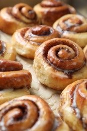 Photo of Tasty cinnamon rolls with cream on parchment paper, closeup