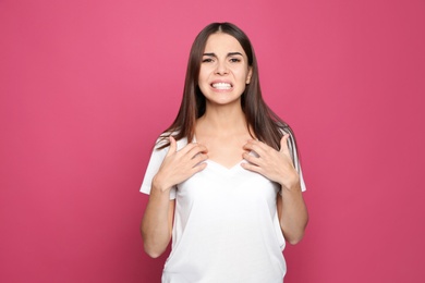 Photo of Young woman scratching chest on color background. Annoying itch