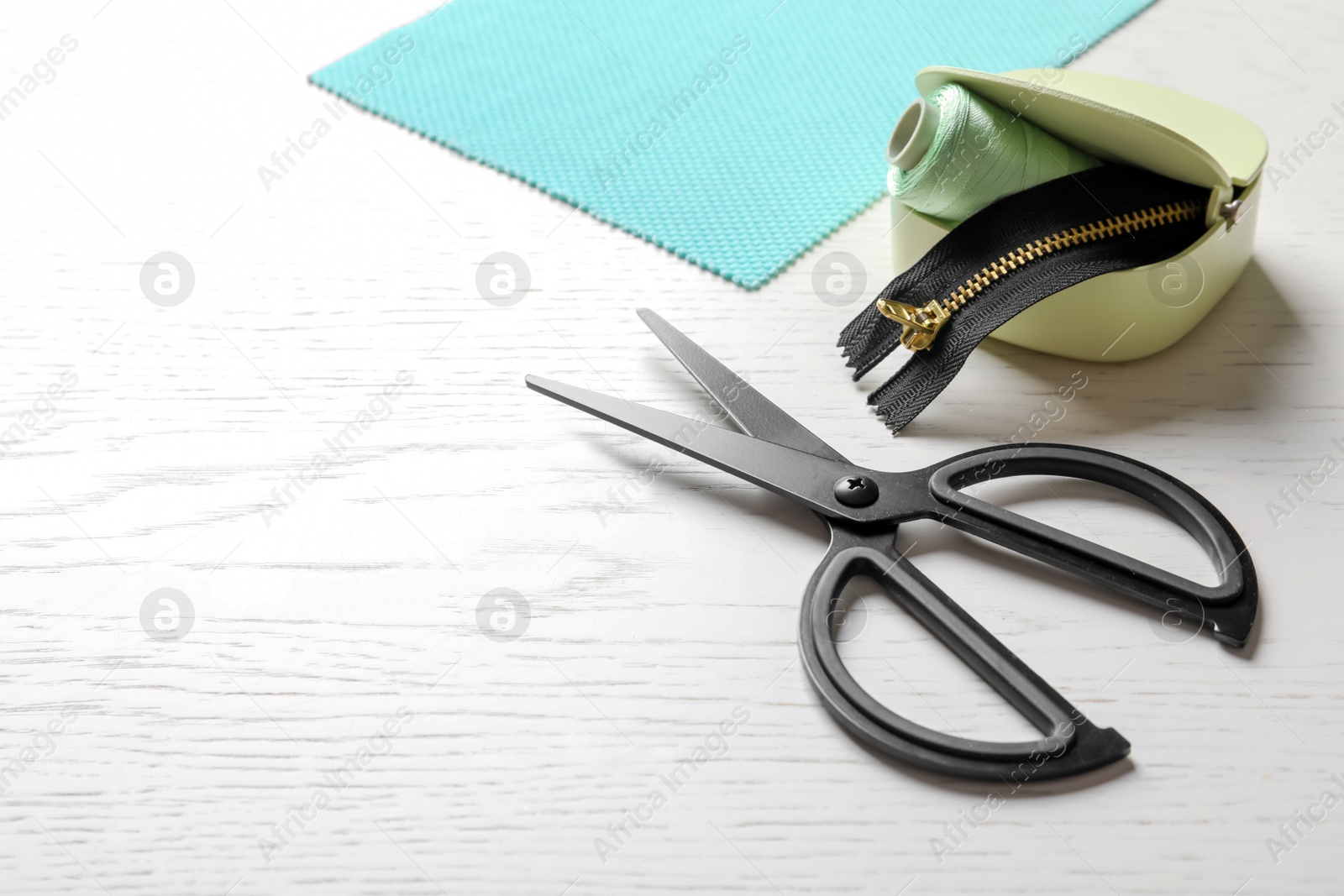 Photo of Set of tailoring accessories and fabric on light background