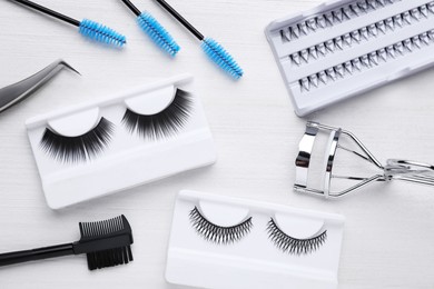 Flat lay composition with false eyelashes and tools on white wooden table