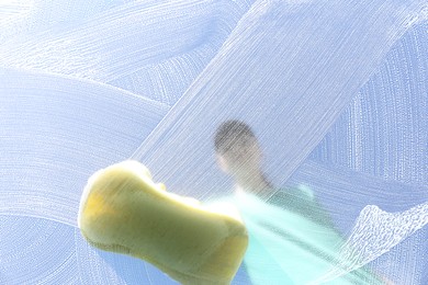 Woman cleaning glass with sponge on sunny day