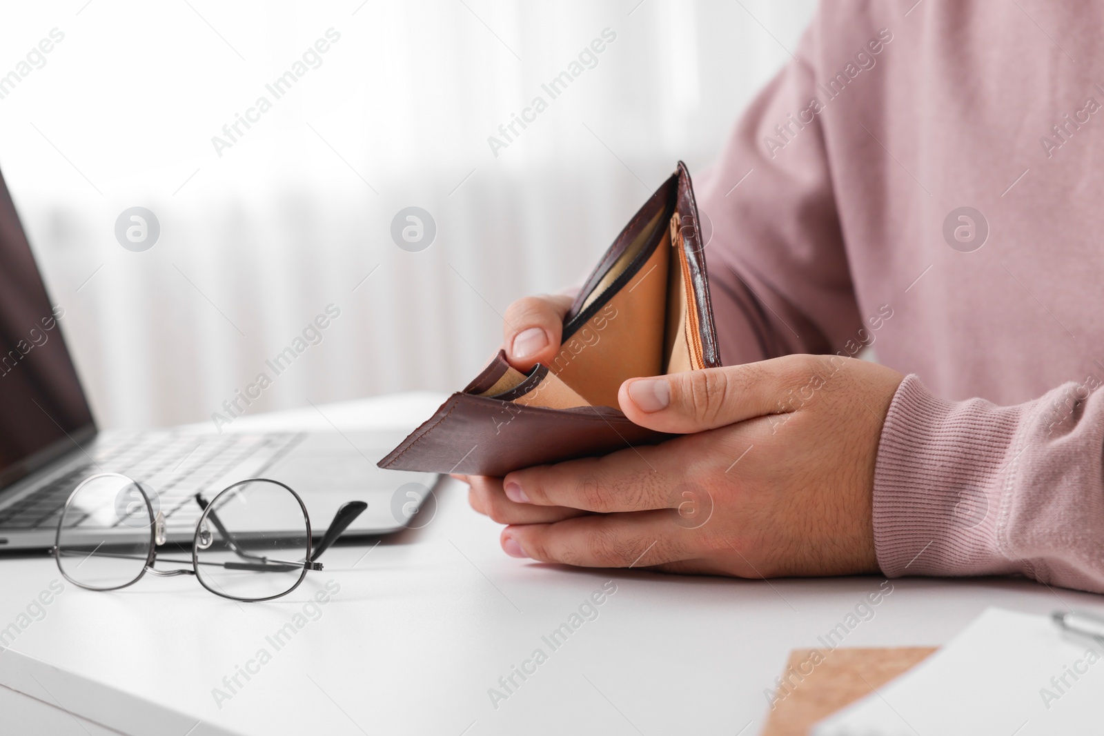 Photo of Man with empty wallet at white table indoors, closeup