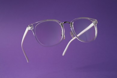 Photo of Stylish pair of glasses on purple background