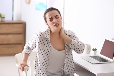 Photo of Woman suffering from neck pain in office. Bad posture problem