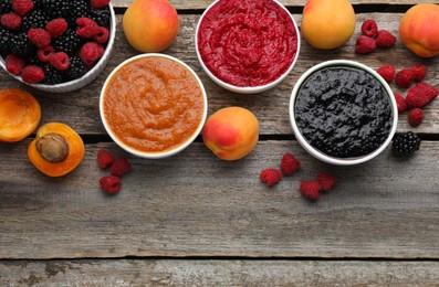 Photo of Different puree in bowls and fresh fruits on wooden table, flat lay. Space for text