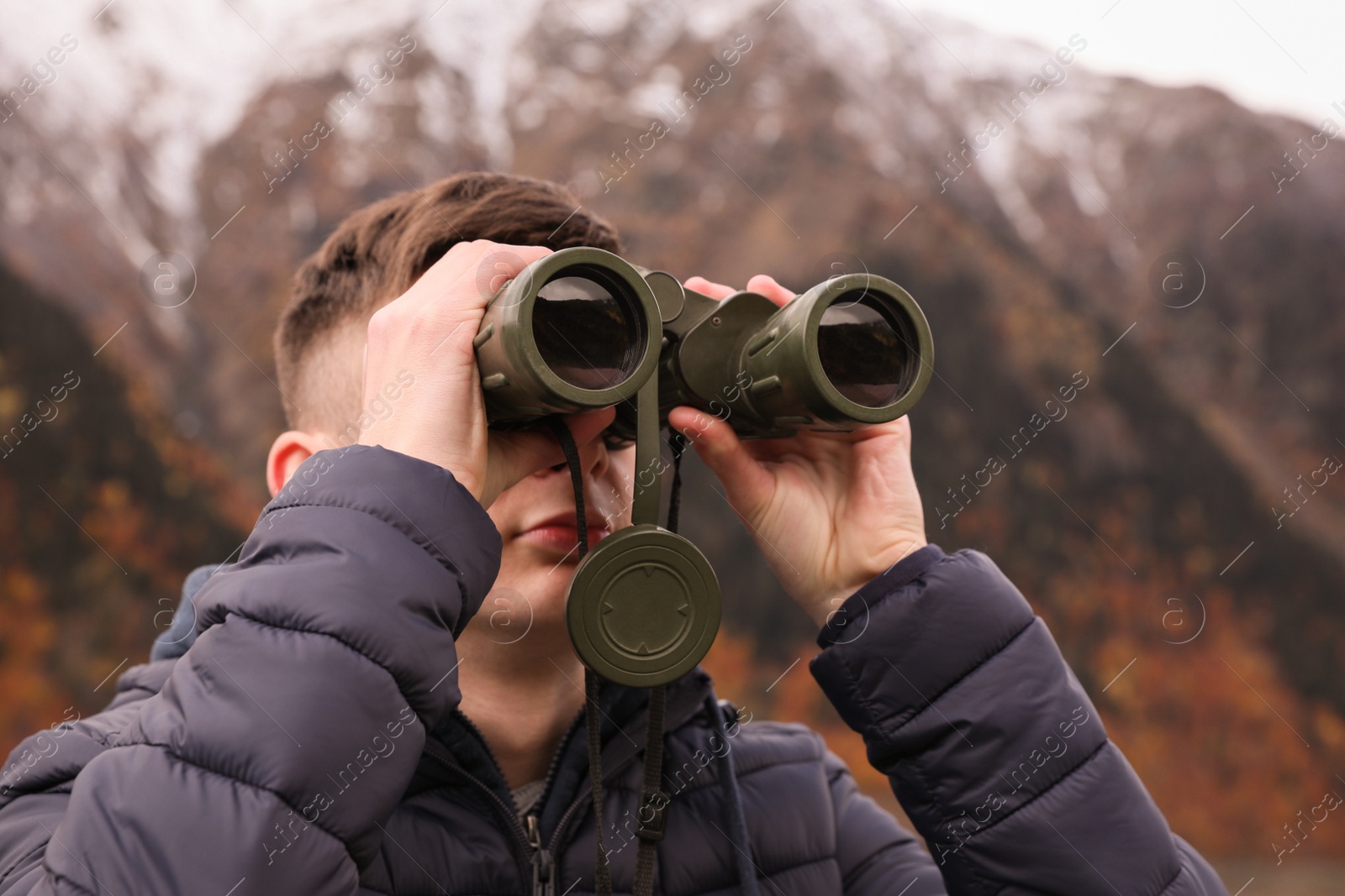 Photo of Boy looking through binoculars in beautiful mountains, closeup