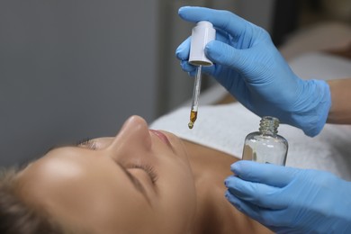 Cosmetologist applying serum on client's face in spa salon