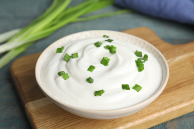 Fresh sour cream with onion on wooden board, closeup