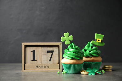 Photo of Decorated cupcakes, wooden block calendar and coins on table. St. Patrick's day celebration