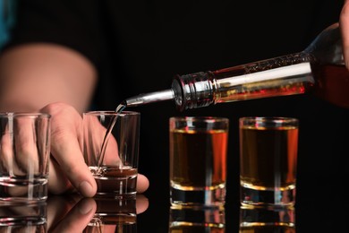 Bartender pouring alcohol drink into shot glass at mirror bar counter, closeup