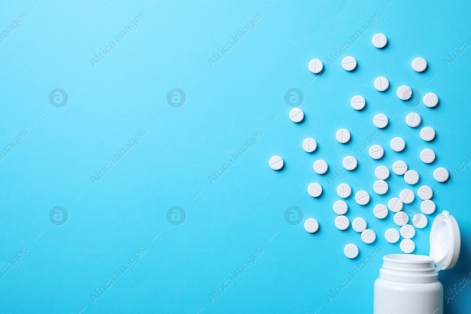 Photo of Bottle with pills on light blue background, flat lay. Space for text