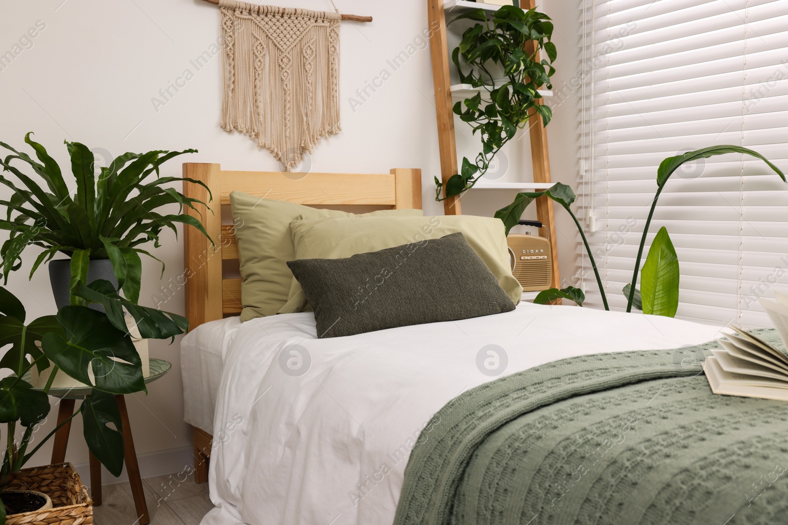 Photo of Large comfortable bed and potted houseplants in stylish bedroom. Interior design