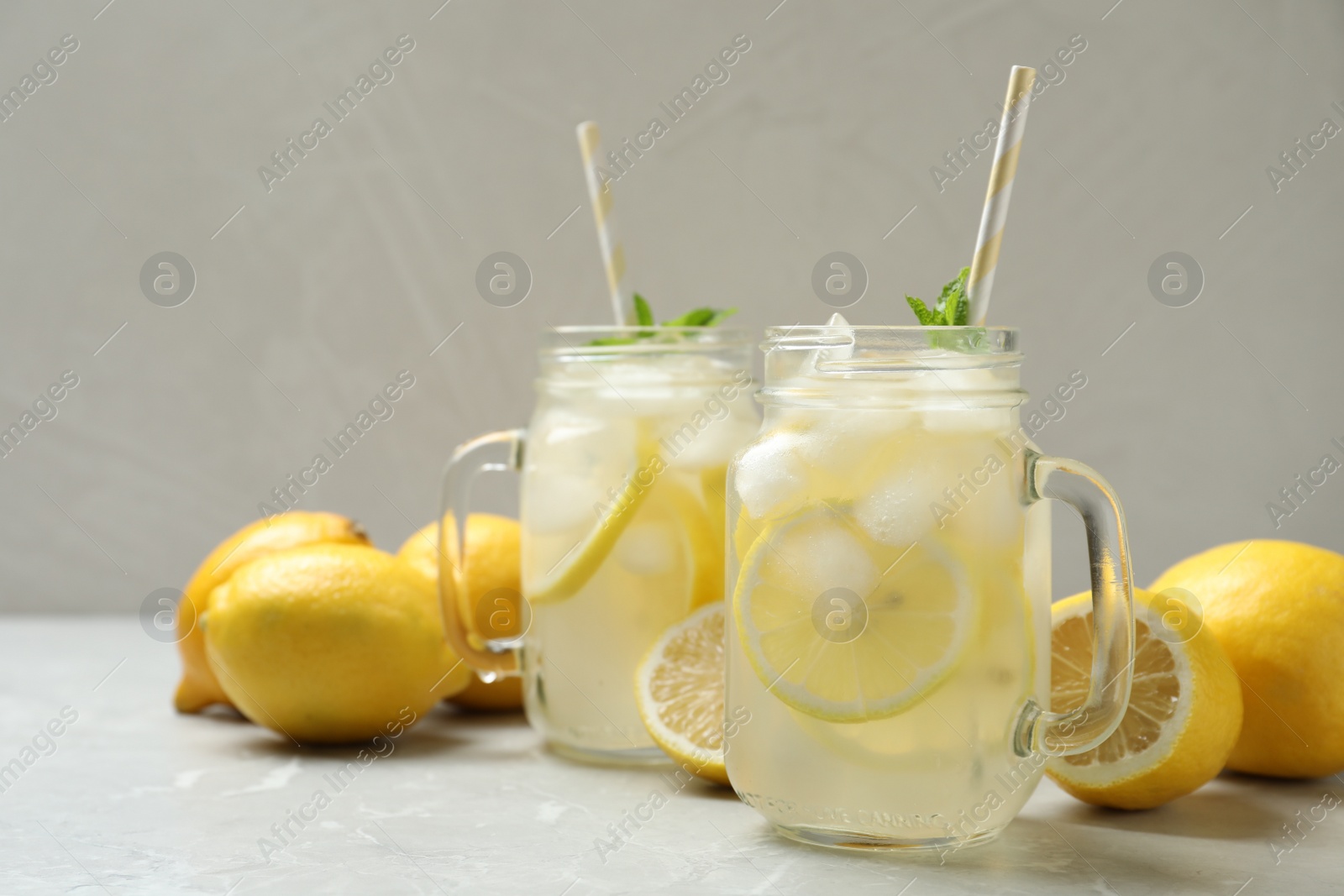 Photo of Natural lemonade with mint and fresh fruits on light grey marble table. Summer refreshing drink