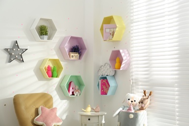 Photo of Hexagon shaped shelves on white wall in nursery. Interior design