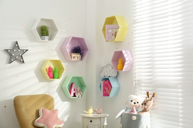 Hexagon shaped shelves on white wall in nursery. Interior design