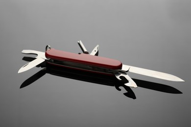 Photo of Compact portable red multitool on grey table, closeup