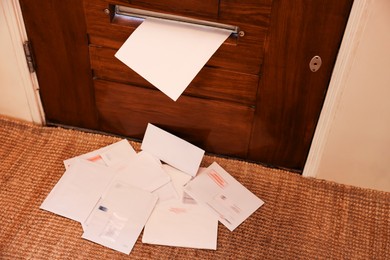 Wooden door with mail slot and many envelopes indoors