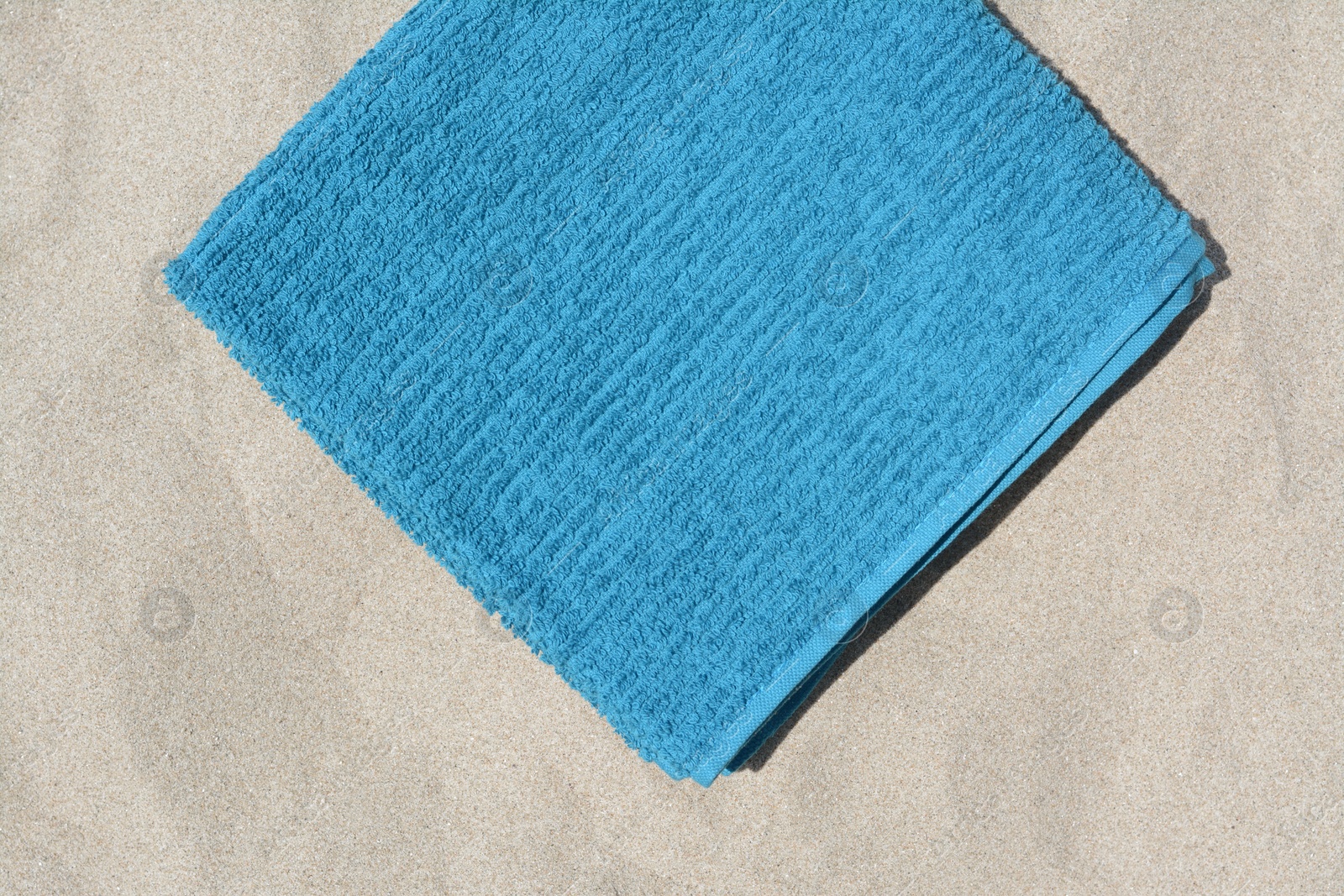 Photo of Soft blue beach towel on sand, top view