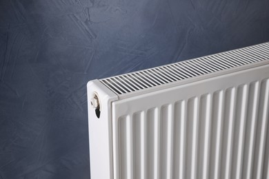 Photo of Modern radiator on grey wall, closeup. Central heating system