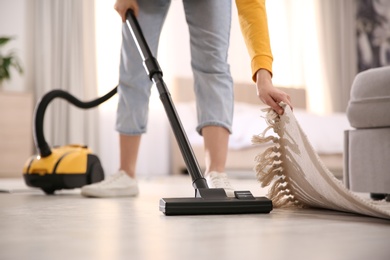 Photo of Young woman using vacuum cleaner at home, closeup