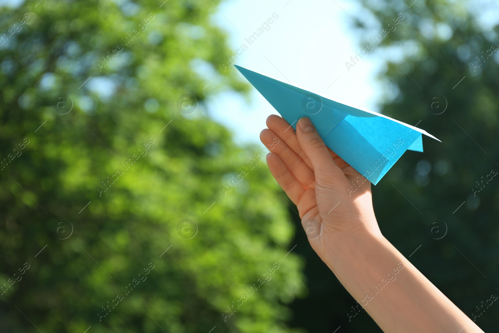 Photo of Woman holding paper plane outdoors, closeup. Space for text