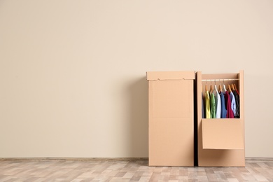 Photo of Wardrobe boxes with clothes against color wall indoors. Space for text