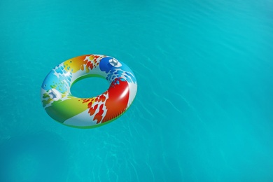 Photo of Colorful inflatable ring floating in swimming pool on sunny day. Space for text