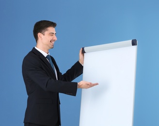 Photo of Business trainer giving presentation on flip chart board against color background