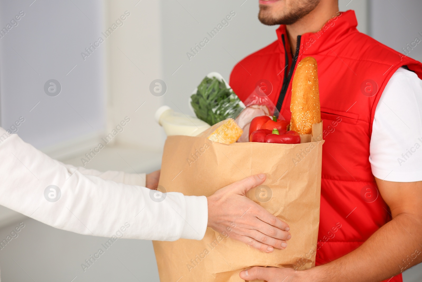 Photo of Male courier delivering food to client indoors, closeup