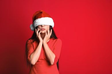 Photo of Young beautiful woman in Santa hat on color background. Christmas celebration