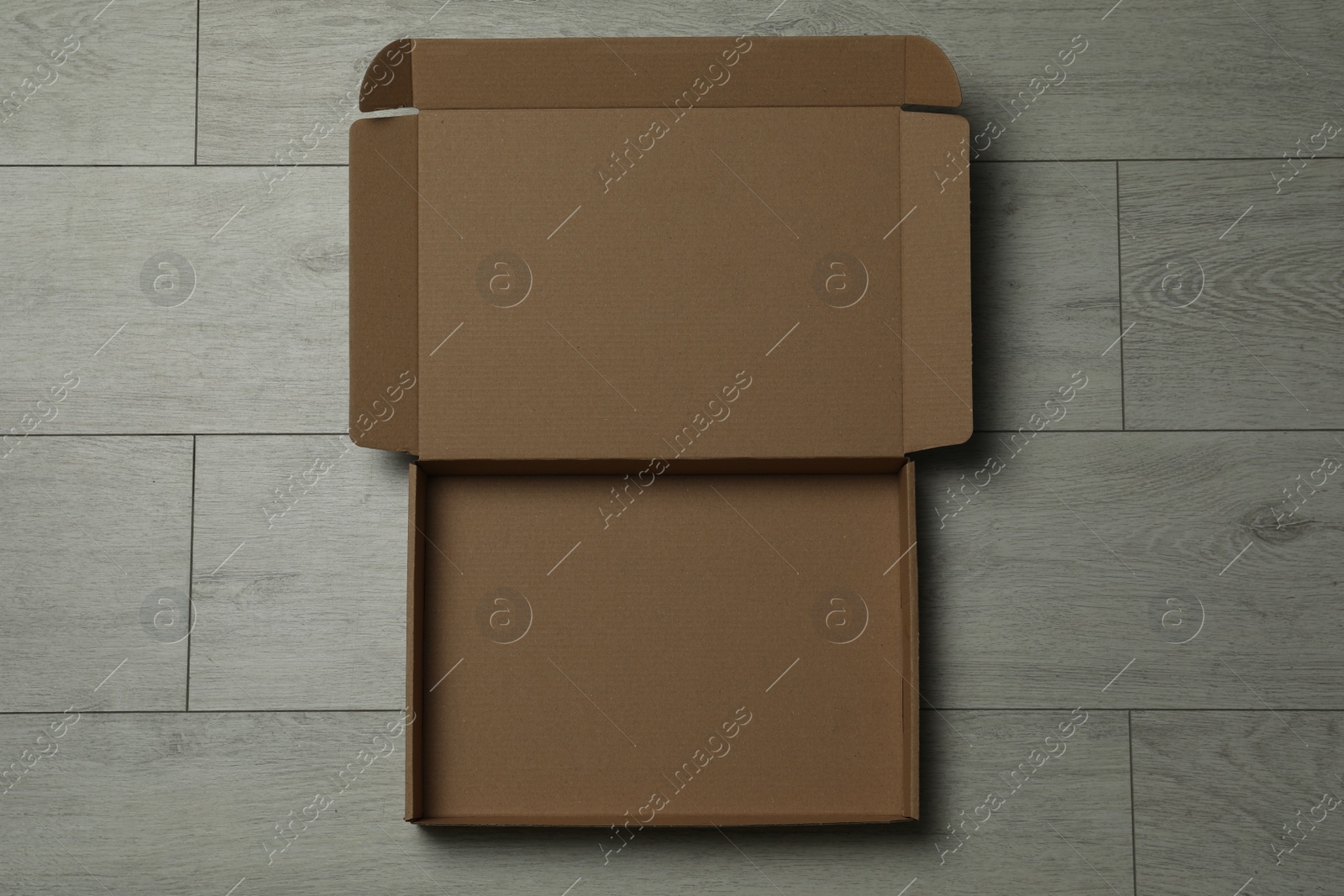 Photo of Empty open cardboard box on floor, top view