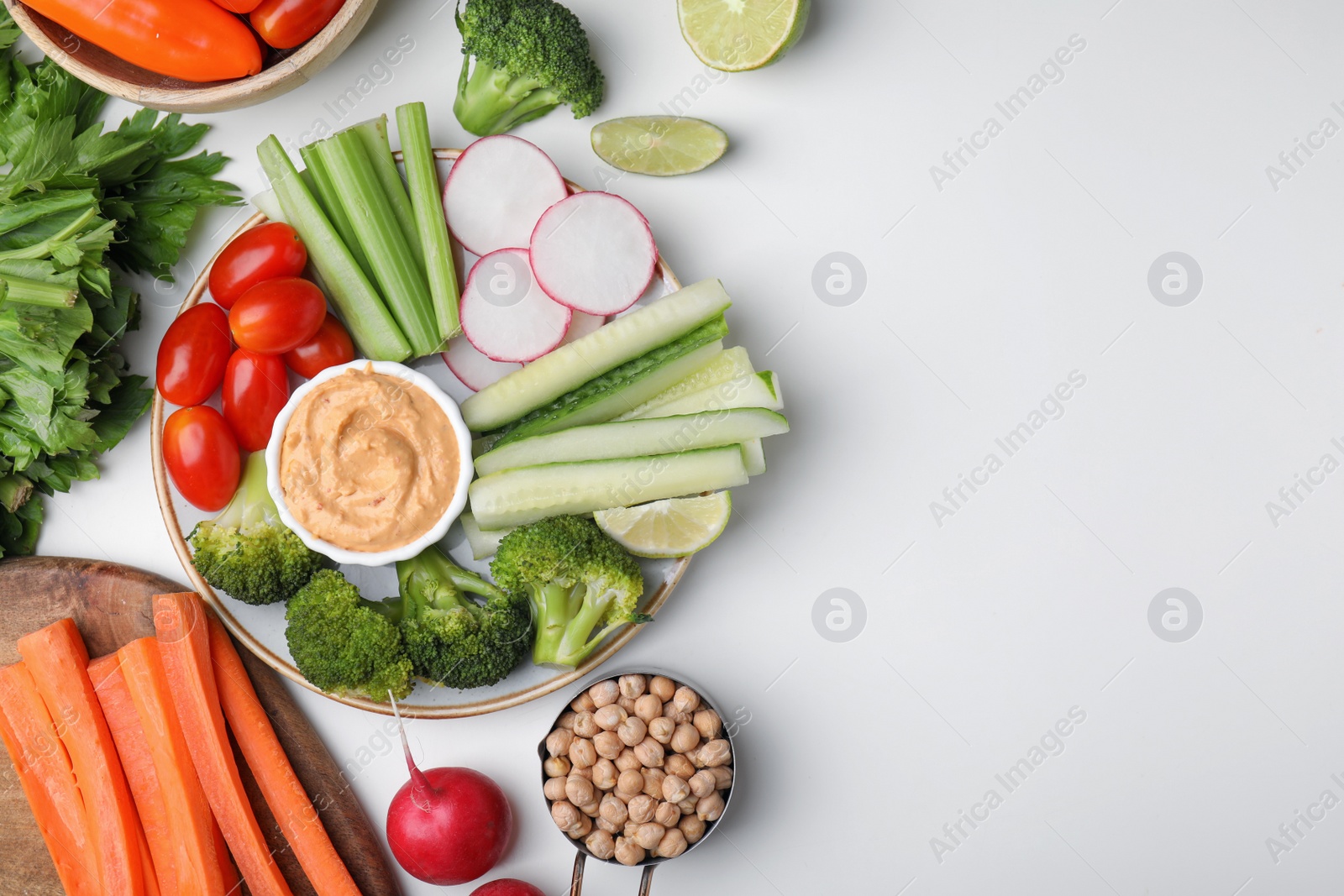 Photo of Plate with delicious hummus and fresh vegetables on white table, flat lay. Space for text