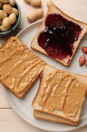 Photo of Delicious toasts with peanut butter, jam and nuts on light wooden table, top view