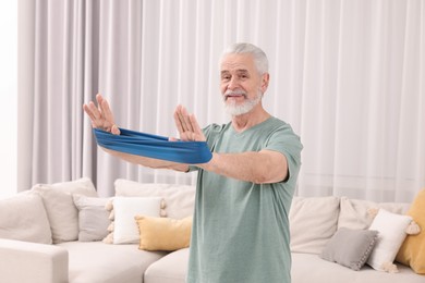 Senior man doing exercise with fitness elastic band at home