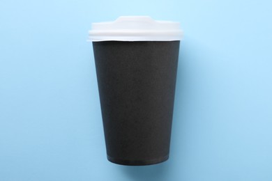 One paper cup on light blue background, top view. Coffee to go