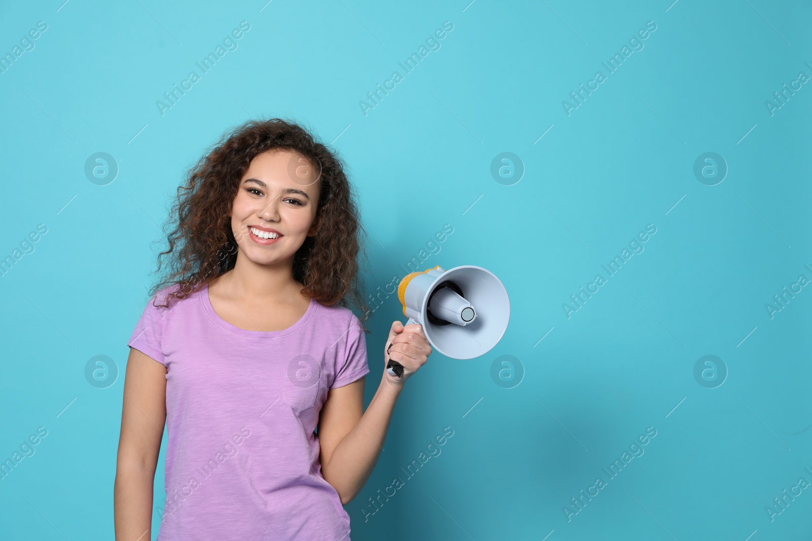 Photo of Young African-American woman with megaphone on color background. Space for text