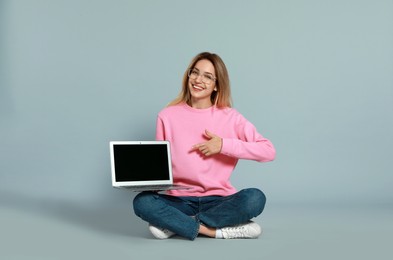 Photo of Young woman with modern laptop on grey background