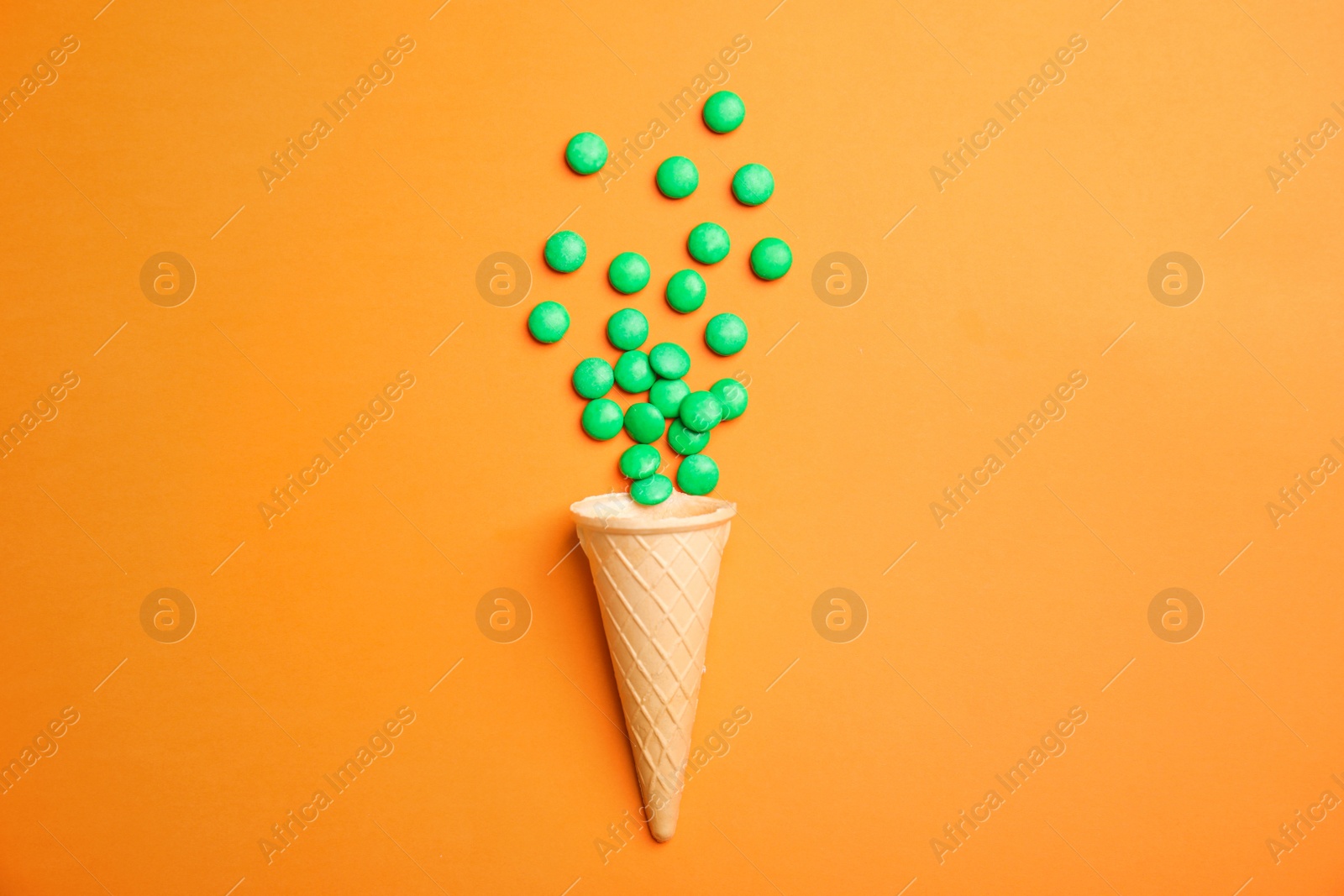 Photo of Flat lay composition with candies and ice cream cone on color background