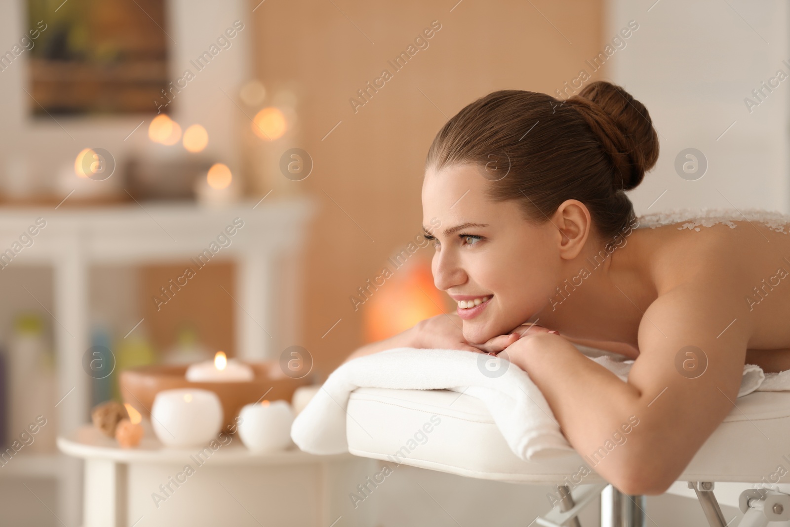 Photo of Beautiful young woman having massage with body scrub in spa salon