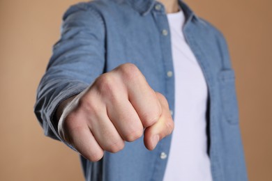 Photo of Man showing fist with space for tattoo on beige background, selective focus