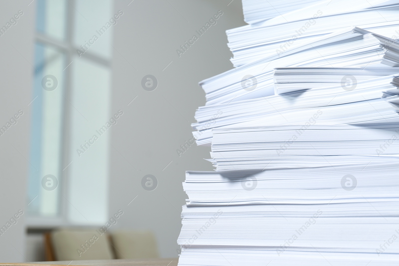 Photo of Stack of paper sheets against blurred background, closeup. Space for text