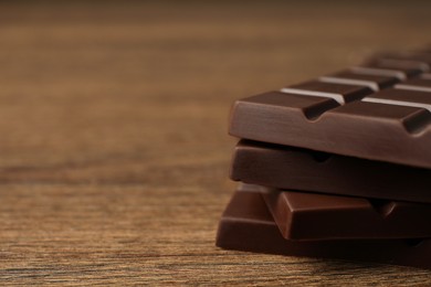 Photo of Pieces of tasty chocolate bars on wooden table, closeup. Space for text