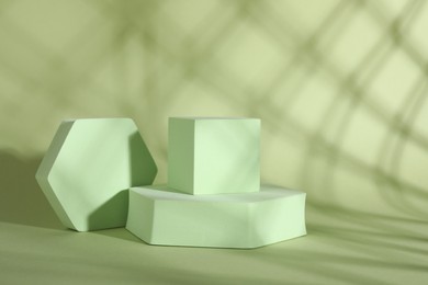 Photo of Presentation of product. Podiums and shadows on light green background. Space for text