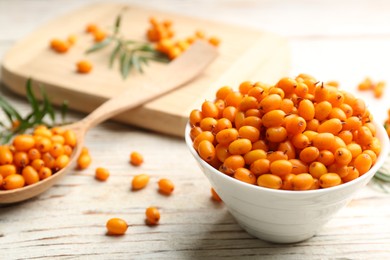 Fresh ripe sea buckthorn in bowl on white wooden table